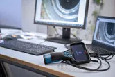 Inspection camera connected to a laptop on an office desk with pipe images on screens.