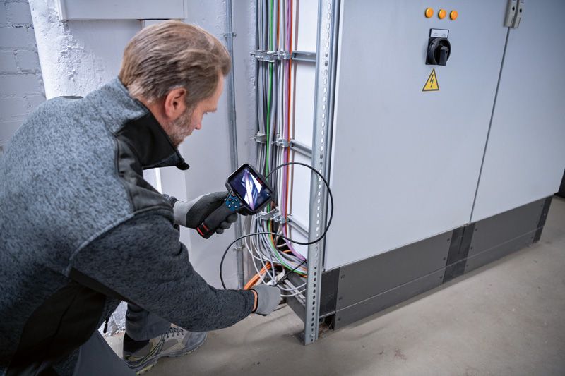 GIC 5-27 C A person wearing safety equipment inspects electrical wiring using an inspection camera.