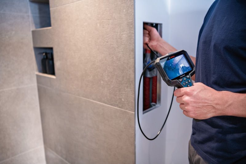 GIC 5-27 C Person uses an inspection camera to examine inside a wall panel.