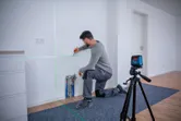 A person marks a wall using a laser leveling tool set on a tripod.