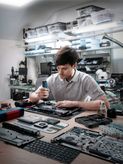 Person assembling electronic devices with a cordless screwdriver in a workshop.