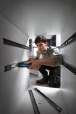 A person uses a cordless screwdriver to install drawer slides inside a cabinet.