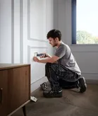 A person installs an electrical outlet cover with a cordless screwdriver.