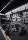 A person repairs an electric scooter using a cordless screwdriver in a workshop.
