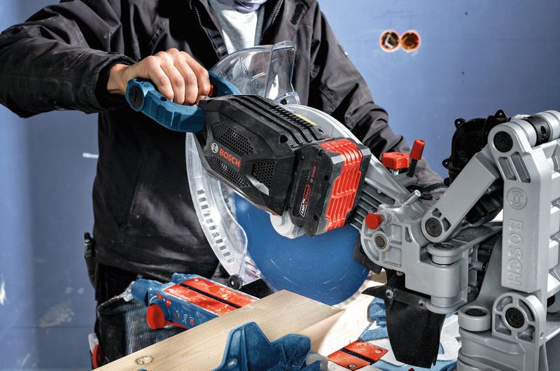 ProCORE18V+ 8.0Ah A person wearing safety equipment uses a miter saw with an 8.0Ah battery pack to cut wood.