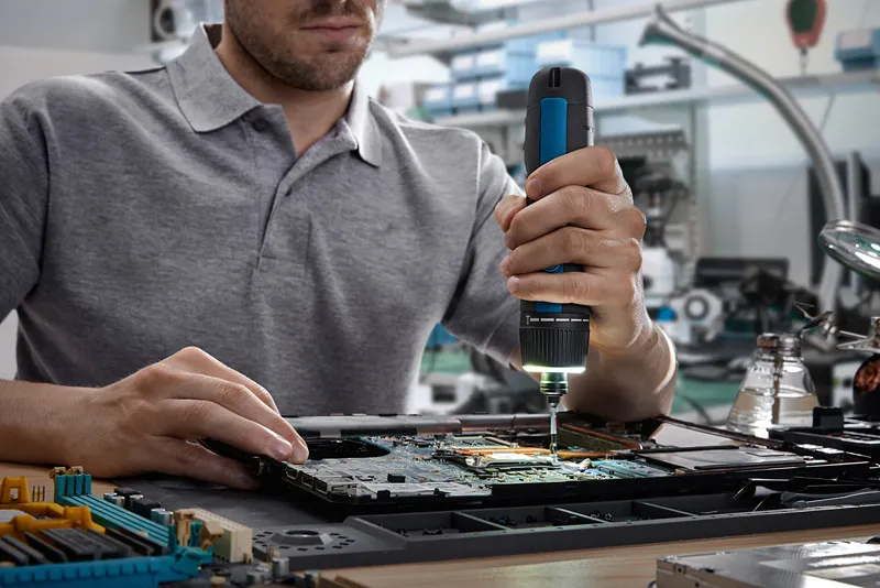 Bosch GO Person using a cordless screwdriver to assemble electronic components on a circuit board.