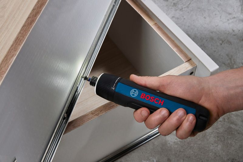 Bosch GO A person uses a cordless screwdriver to assemble a metal cabinet drawer.