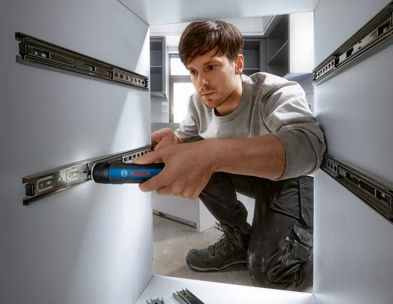 Bosch GO A person installs drawer slides in cabinetry using a cordless screwdriver.