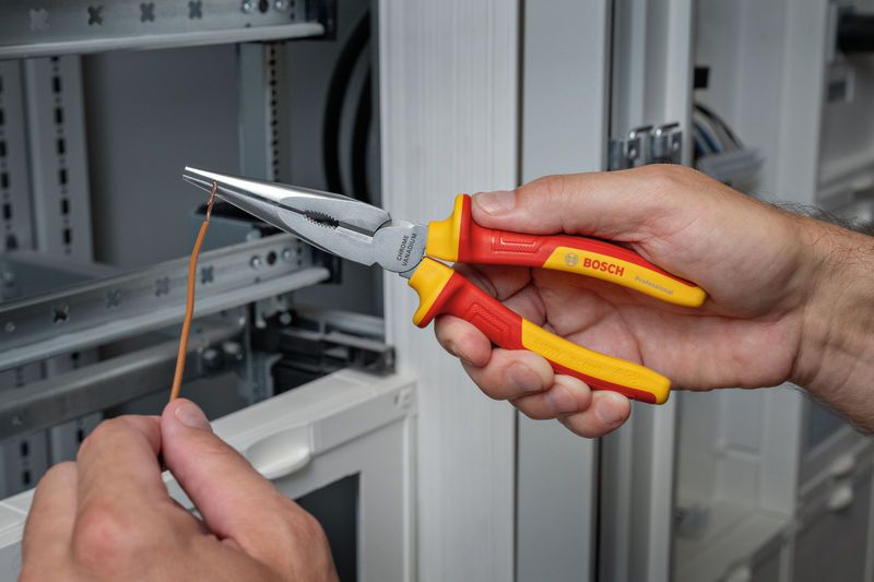 VDE Long Nose Pliers straight 200mm A person grips insulated pliers, shaping a wire near an electrical panel.