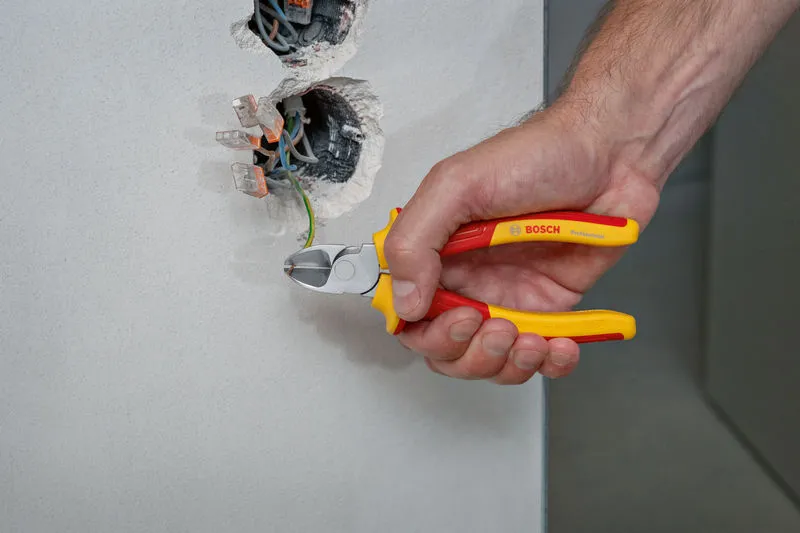 VDE Diagonal Side Cutter 160mm A person uses insulated pliers to cut a green wire from an electrical wall box.