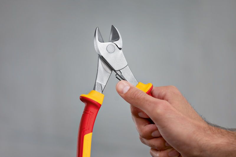 VDE High Leverage Dg. Side Cutter 200mm A person holds insulated diagonal side cutter pliers with red and yellow handles.