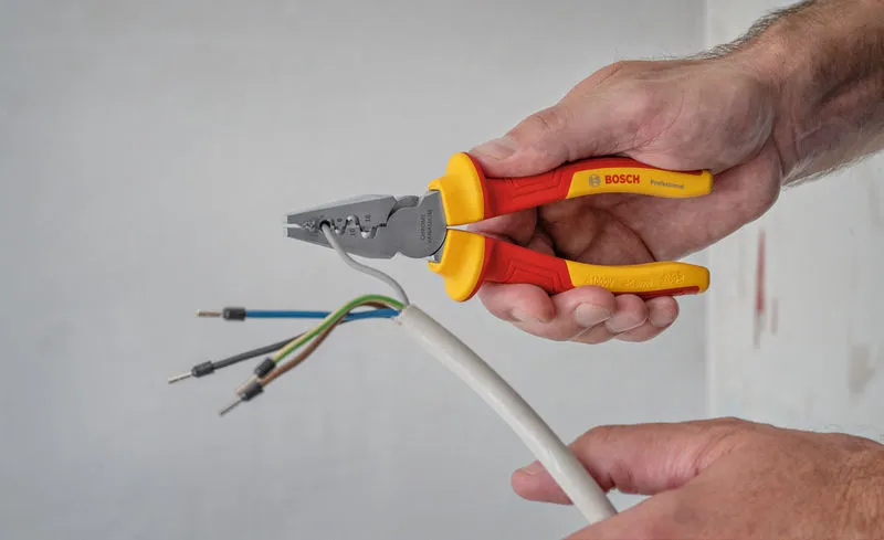 VDE Crimping Pliers 180mm Person strips insulation from electrical wires using insulated pliers.