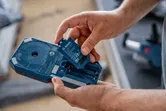 Person inserts a battery pack into a blue power tool housing.