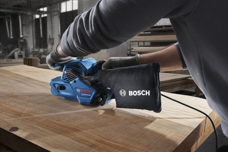 GBS 750 A person wearing safety equipment sands a wooden board with a blue belt sander.