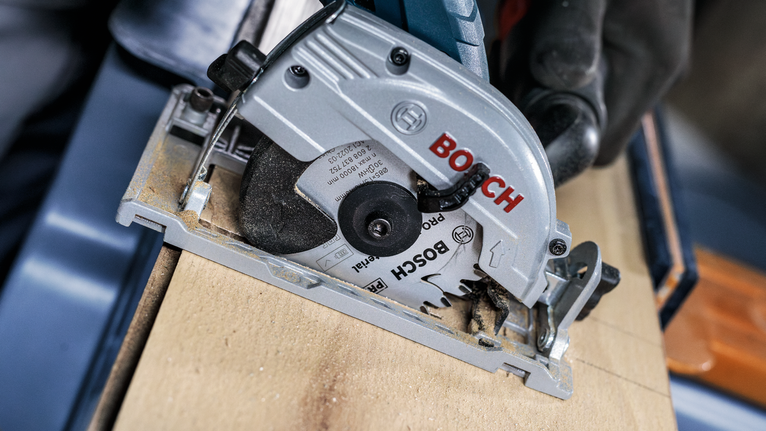 PRO Multi Material cordless Circular Saw Blade, 85 x 1.5 x 15 mm Person wearing safety equipment cuts wood using a circular saw.