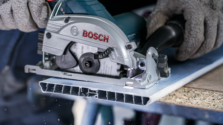 PRO Multi Material cordless Circular Saw Blade, 85 x 1.5 x 15 mm Person wearing safety equipment cuts a metal sheet with a circular saw.