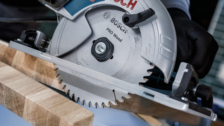 PRO Wood Circular Saw Blade, 184 x 2 x 20 mm A person wearing safety equipment uses a circular saw to cut a wooden board.
