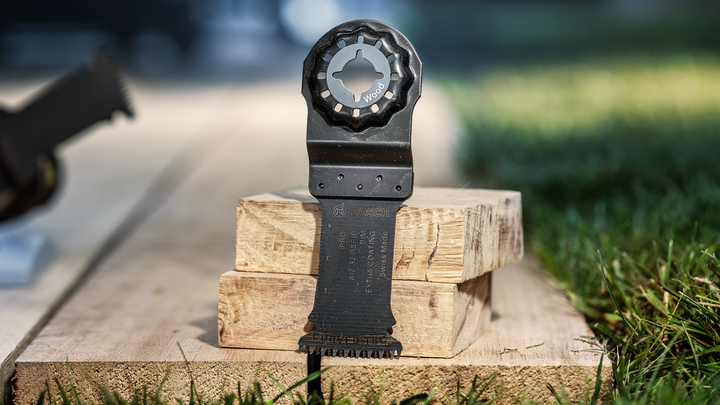 Saw blade attachment standing upright on stacked wooden planks outdoors.