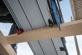 Track saw cutting through a wooden beam on a construction site.