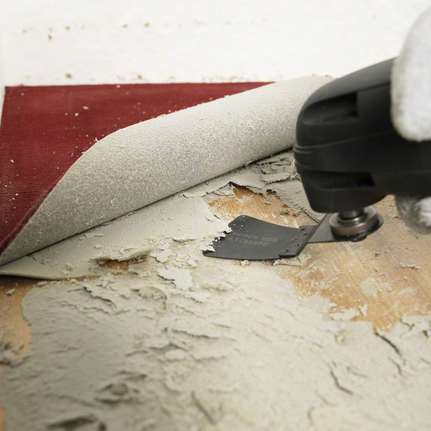 13-piece universal set Person wearing safety equipment uses a power tool to remove adhesive under flooring.