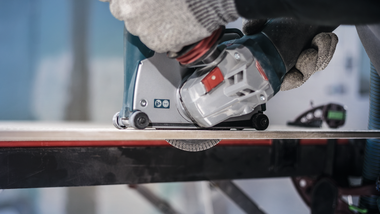 PRO Ceramic Diamond Disc, 105 x 20/16 mm Person wearing safety equipment operates a power tool to cut a tile.
