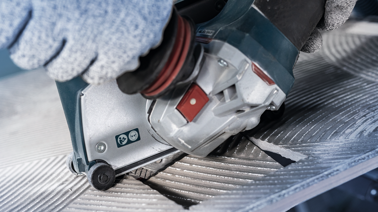 PRO Ceramic Diamond Disc, 105 x 20/16 mm Person wearing safety equipment operates a power tool to cut a grooved metal surface.