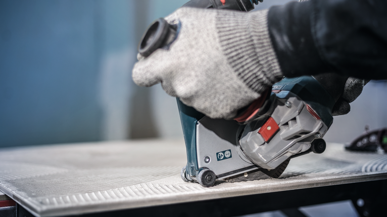 PRO Ceramic Diamond Disc, 105 x 20/16 mm Person wearing safety equipment uses a power tool to cut a tile.