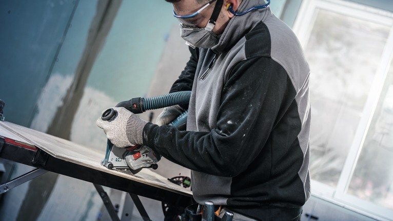 PRO Ceramic Diamond Disc, 105 x 20/16 mm Person wearing safety equipment trims wood with a power tool attached to a vacuum hose.