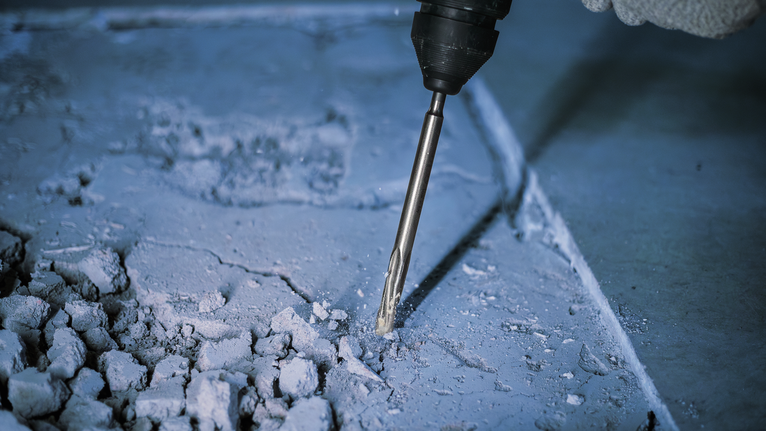 PRO SDS plus-5C Pointed Chisel, 250 mm A person wearing safety equipment uses a rotary hammer to break concrete.