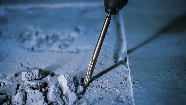 PRO SDS plus-5C Pointed Chisel, 250 mm Rotary hammer breaking concrete in a construction setting.