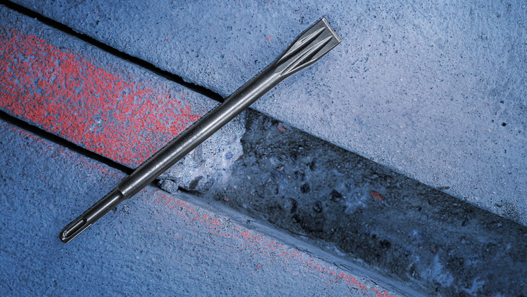 PRO SDS plus-5C Flat Chisel, 20 x 250 mm Chisel drill bit placed on a concrete slab with a groove.