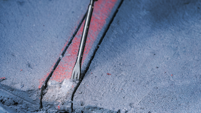 PRO SDS plus-5C Flat Chisel, 20 x 250 mm Chisel breaking a groove into a marked concrete surface.