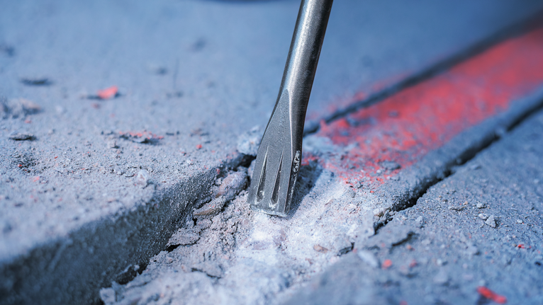 PRO SDS plus-5C Flat Chisel, 20 x 250 mm Chisel bit breaking concrete along a marked line.