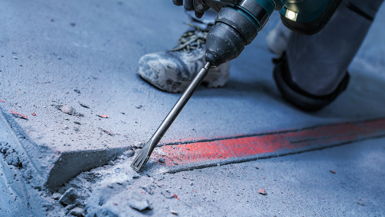PRO SDS plus-5C Flat Chisel, 20 x 250 mm Person wearing safety equipment uses a power tool to break concrete.