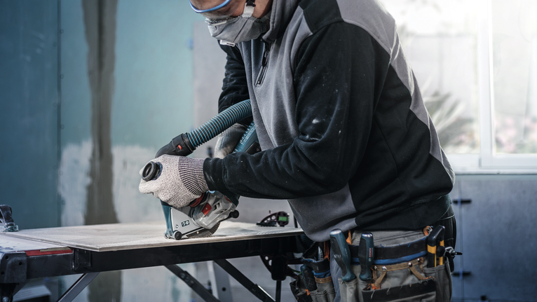 PRO Ceramic Diamond Disc, 105 x 20/16 mm Person wearing safety equipment cuts a tile with a circular saw at a workbench.