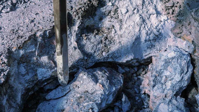 PRO HEX-4C Pointed Chisel 28 mm, 28 x 520 mm Chisel breaking through a rough surface of stone.