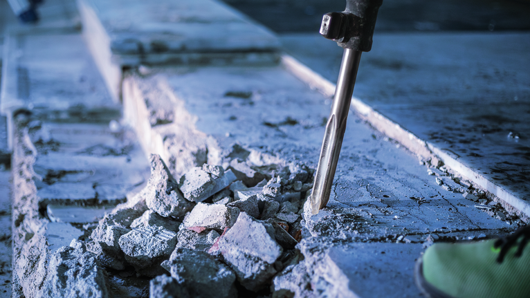 PRO HEX-5C Pointed Chisel 30 mm, 30 x 400 mm Demolition hammer breaking concrete on a construction site.