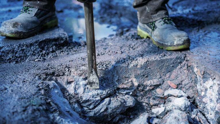 PRO HEX-4C Flat Chisel 30 mm, 35 x 400 mm A person wearing safety equipment breaks concrete with a demolition tool.
