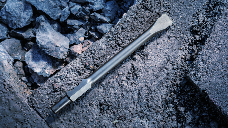 PRO HEX-4C Flat Chisel 30 mm, 35 x 400 mm Flat chisel bit rests on rough concrete among scattered debris.