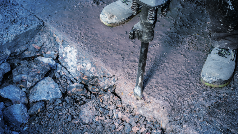 PRO HEX-4C Flat Chisel 30 mm, 35 x 400 mm Person wearing safety equipment breaks concrete with a demolition tool.