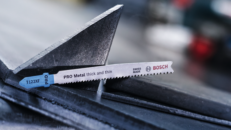 PRO Metal thick and thin T123XF Jigsaw Blade, 100 mm, 3 pcs Jigsaw blade resting on a metal beam in an industrial setting.