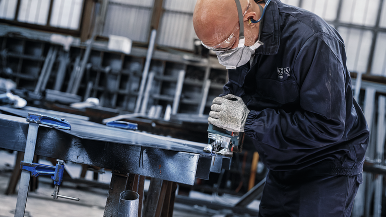 PRO Metal thick and thin T123XF Jigsaw Blade, 100 mm, 3 pcs Person wearing safety equipment uses a power saw to cut metal in a workshop.