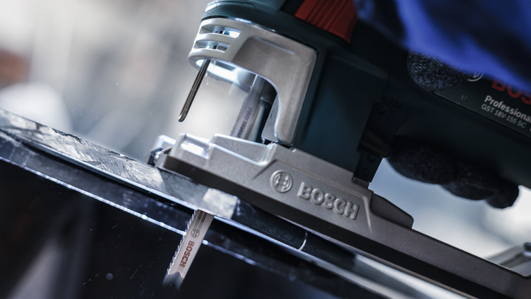 PRO Metal thick and thin T123XF Jigsaw Blade, 100 mm, 3 pcs A person wearing safety equipment uses a jigsaw to cut a black metal sheet.