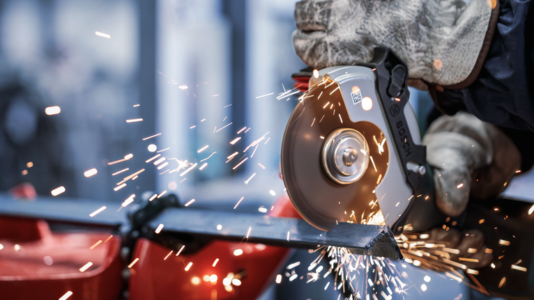 PRO Metal Bonded Cutting Disc, 125 x 1.6 x 22.23 mm, X-Lock Person wearing safety equipment uses an angle grinder to cut metal, producing sparks.