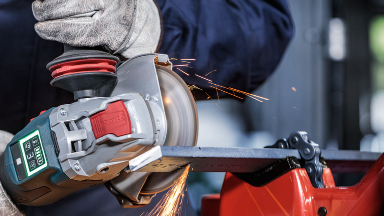 PRO Metal Bonded Cutting Disc, 125 x 1.6 x 22.23 mm, X-Lock A person wearing safety equipment grinds metal with an angle grinder, creating sparks.