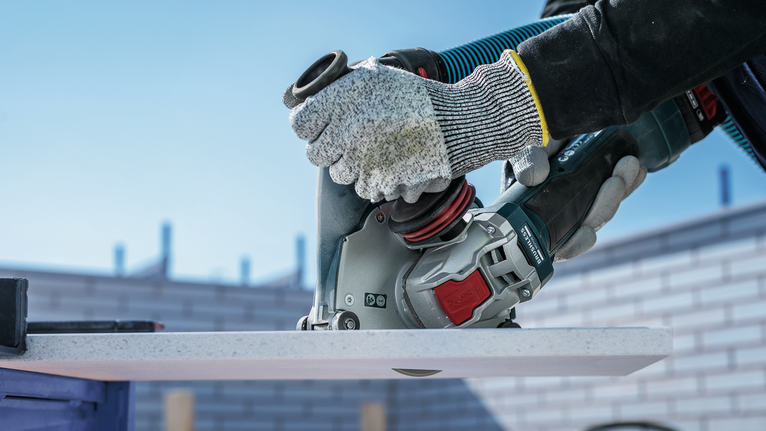 PRO Multi Material X-Lock Cutting Disc, 125 x 1 x 22.23 mm Person wearing safety equipment uses a power tool to cut a white board.