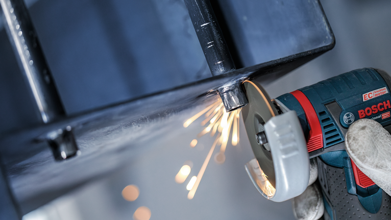 PRO Stainless Steel and Metal Grinding Disc, 76 x 4 x 10 mm A person wearing safety equipment grinds a metal beam, creating sparks.