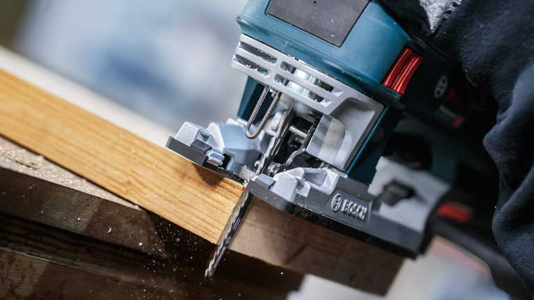 PRO Wood precise T144DP Jigsaw Blade, 100 mm, 5 pcs A person wearing safety equipment uses a jigsaw to cut a wooden board.