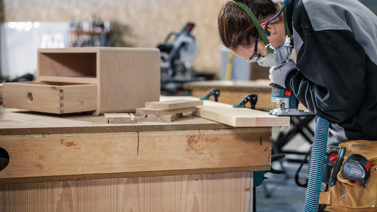 PRO Wood precise T144DP Jigsaw Blade, 100 mm, 5 pcs Person wearing safety equipment uses a power tool to shape wooden boards on a workbench.