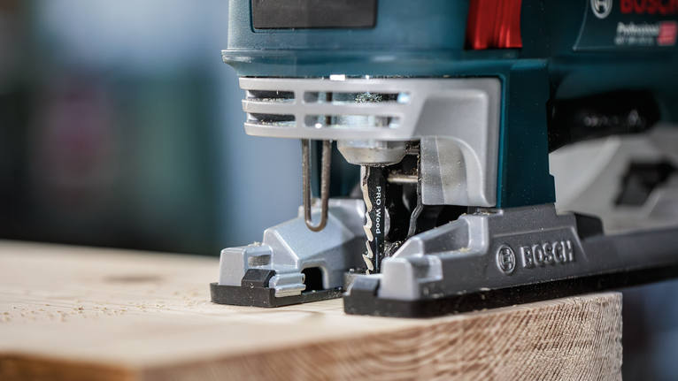 PRO Wood precise T144DP Jigsaw Blade, 100 mm, 5 pcs Jigsaw cutting through a wooden plank in a workshop setting.